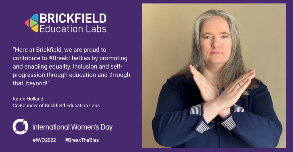 Karen Holland, Co Founder of Brickfield is photographed hands crossed, striking the breaking the bias pose. The text reads "Here at Brickfield, we are proud to contribute to #BreakTheBias by promoting and enabling equality, inclusion and self-progression through education and through that, beyond!"