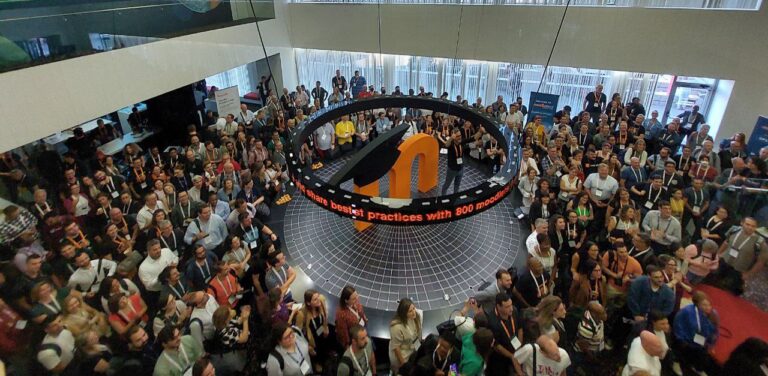 A room full of people. In the middle, a big platform with Moodle’s logo and Martin Dougiamas standing next to it.